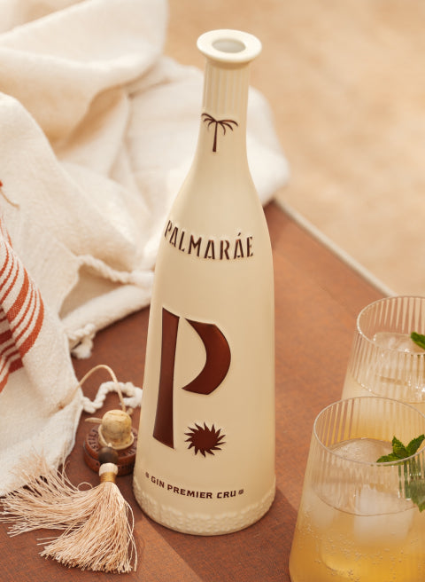 Bottle of Palmarae surrounded by a glass and a beach towel.